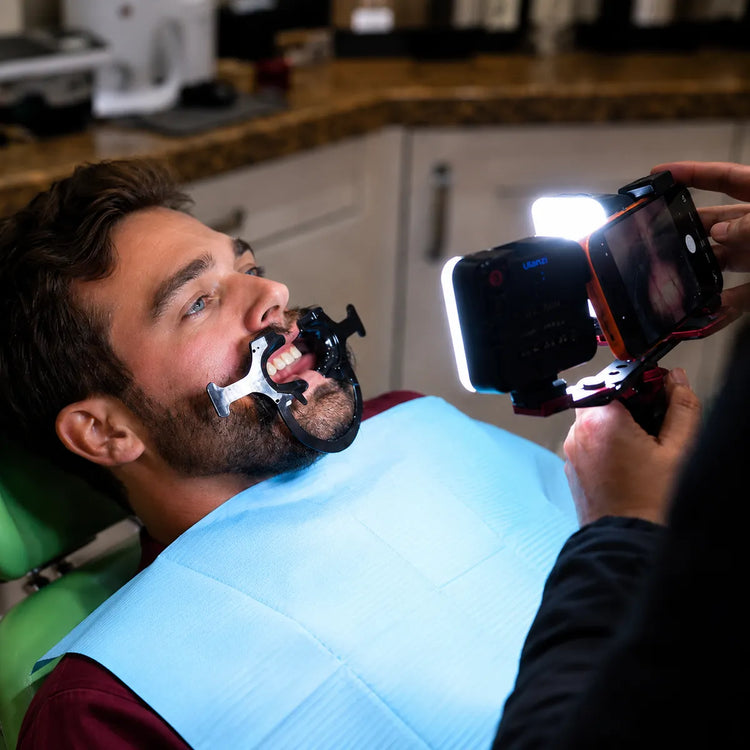 Close-up of a dentist photographing a patient's teeth with a smartphone and twin light