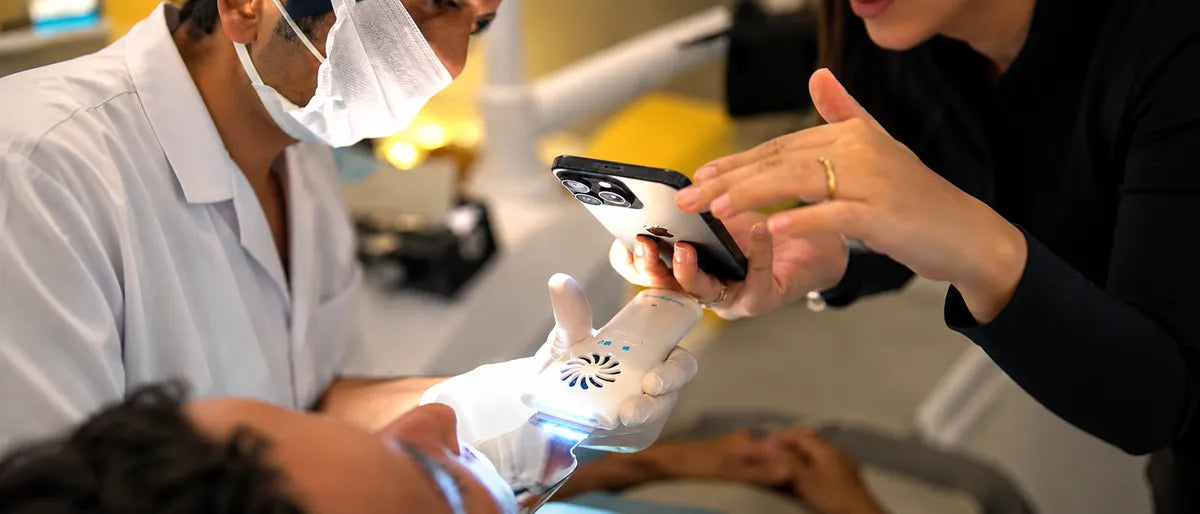Dentist and assistant using a smartphone dental light to photograph a patient chairside