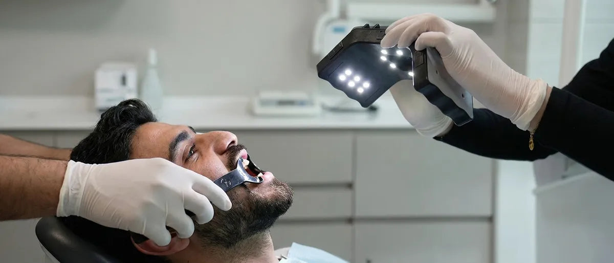 Dentist using an LED dental light to photograph a patient's teeth with a retractor