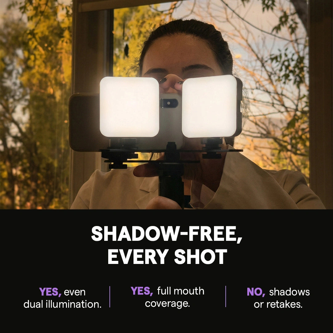 Dentist holding dual LED lights with smartphone for shadow-free photography.
